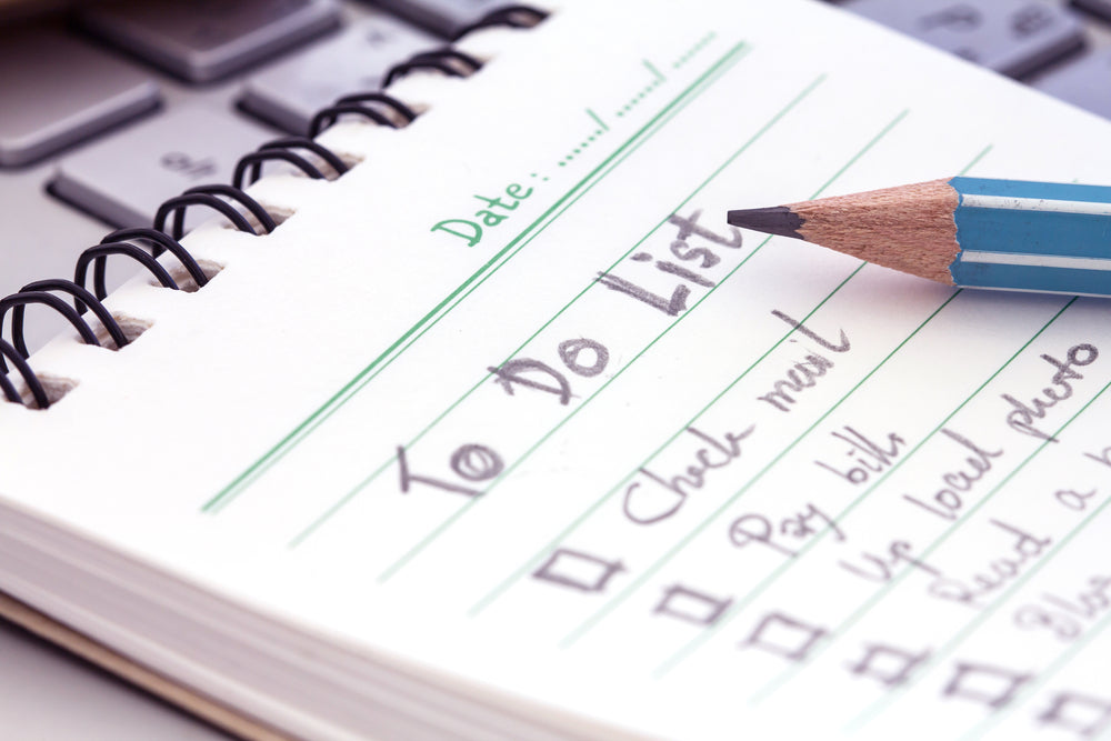 A notebook with a handwritten to-do list and a pencil placed on a keyboard, symbolizing task planning and productivity.