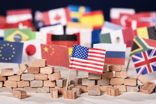 Miniature flags of various countries, including the US, China, and UK, placed among small bricks, symbolizing global relations or diplomacy.