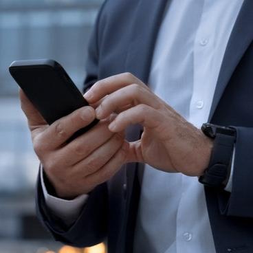 Business professional in a suit using a smartphone, representing communication and connectivity in a corporate setting.