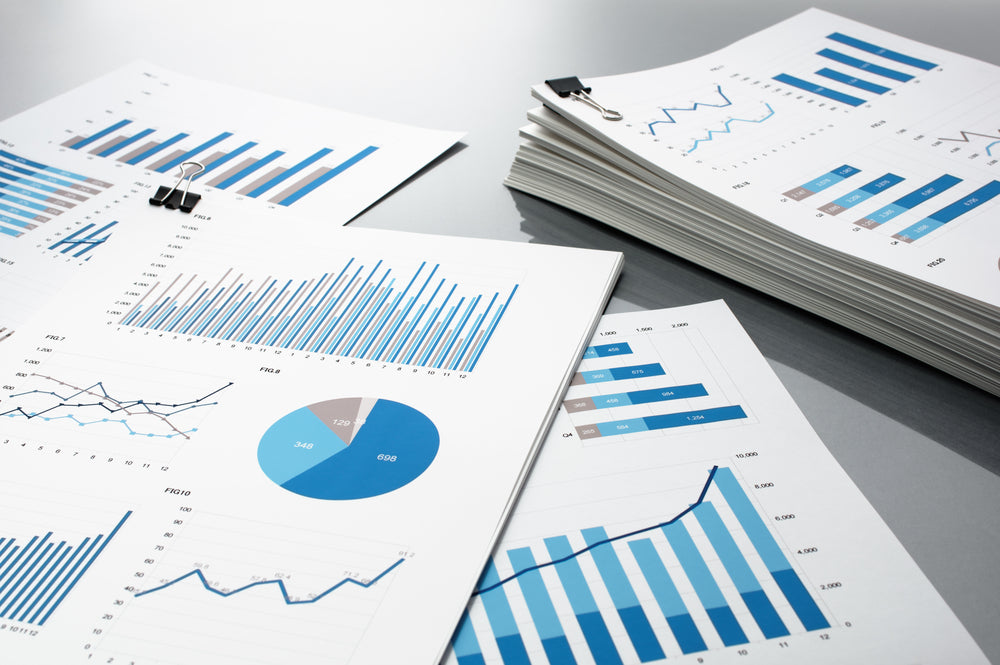 Stack of financial documents with charts, graphs, and pie diagrams, illustrating data analysis and business performance reports.